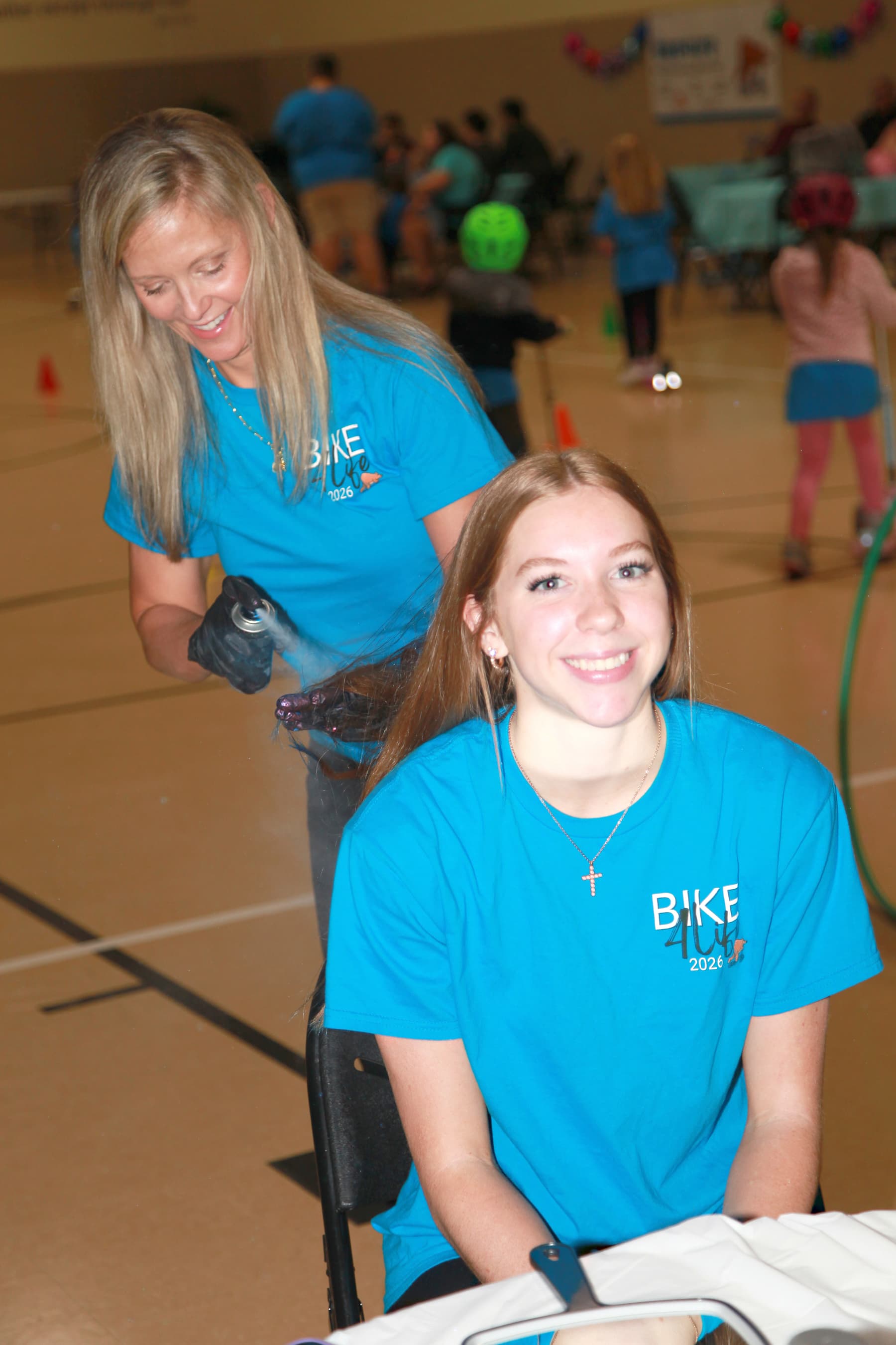 A volunteer mists a rider's hair to cool down during Bike4Life